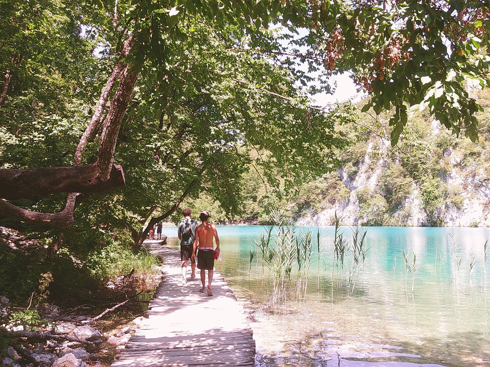 Dois amigos num passadiço junto à água azul
