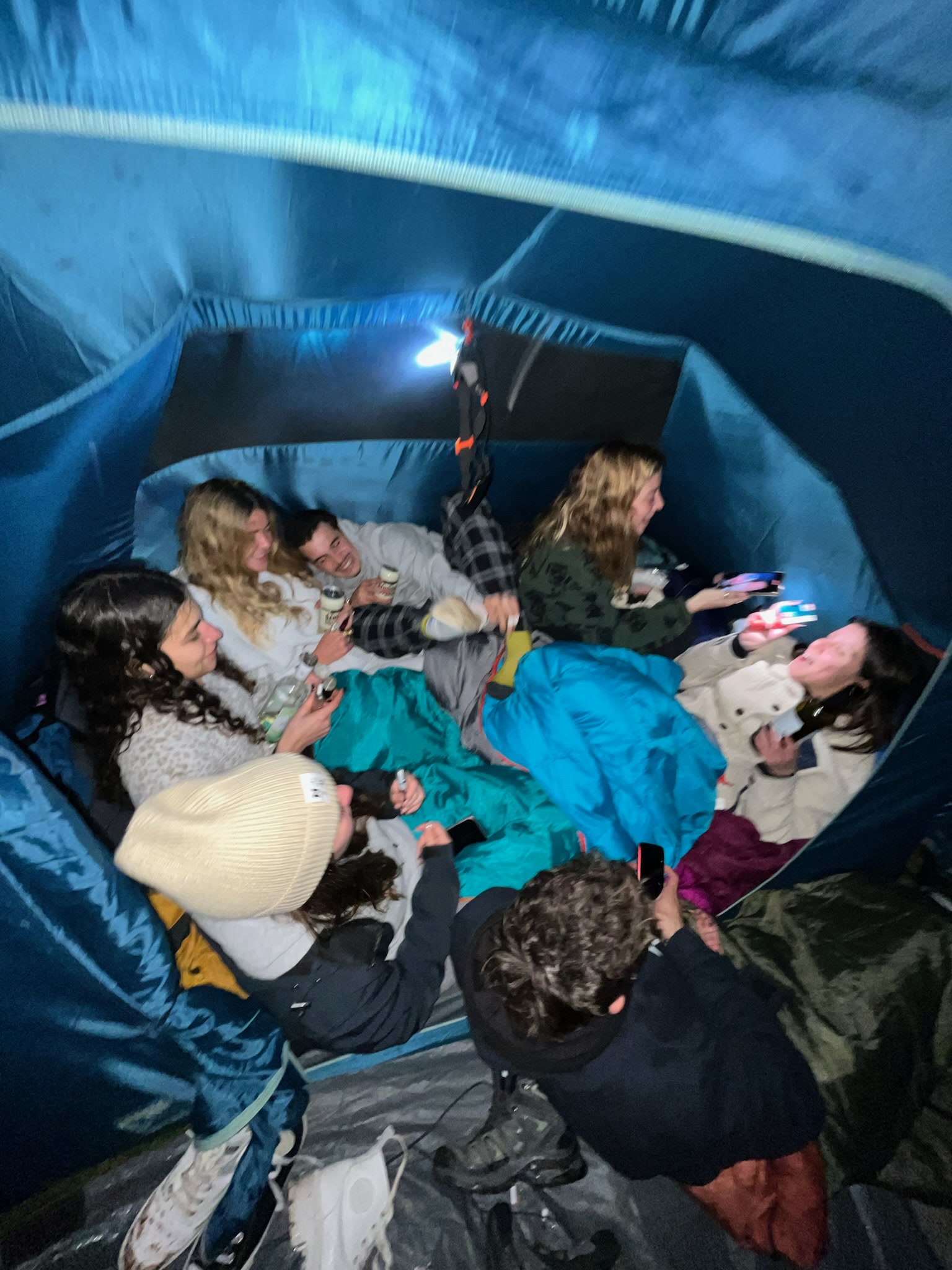 Amigos juntos dentro da tenda azul, antes de a água entrar