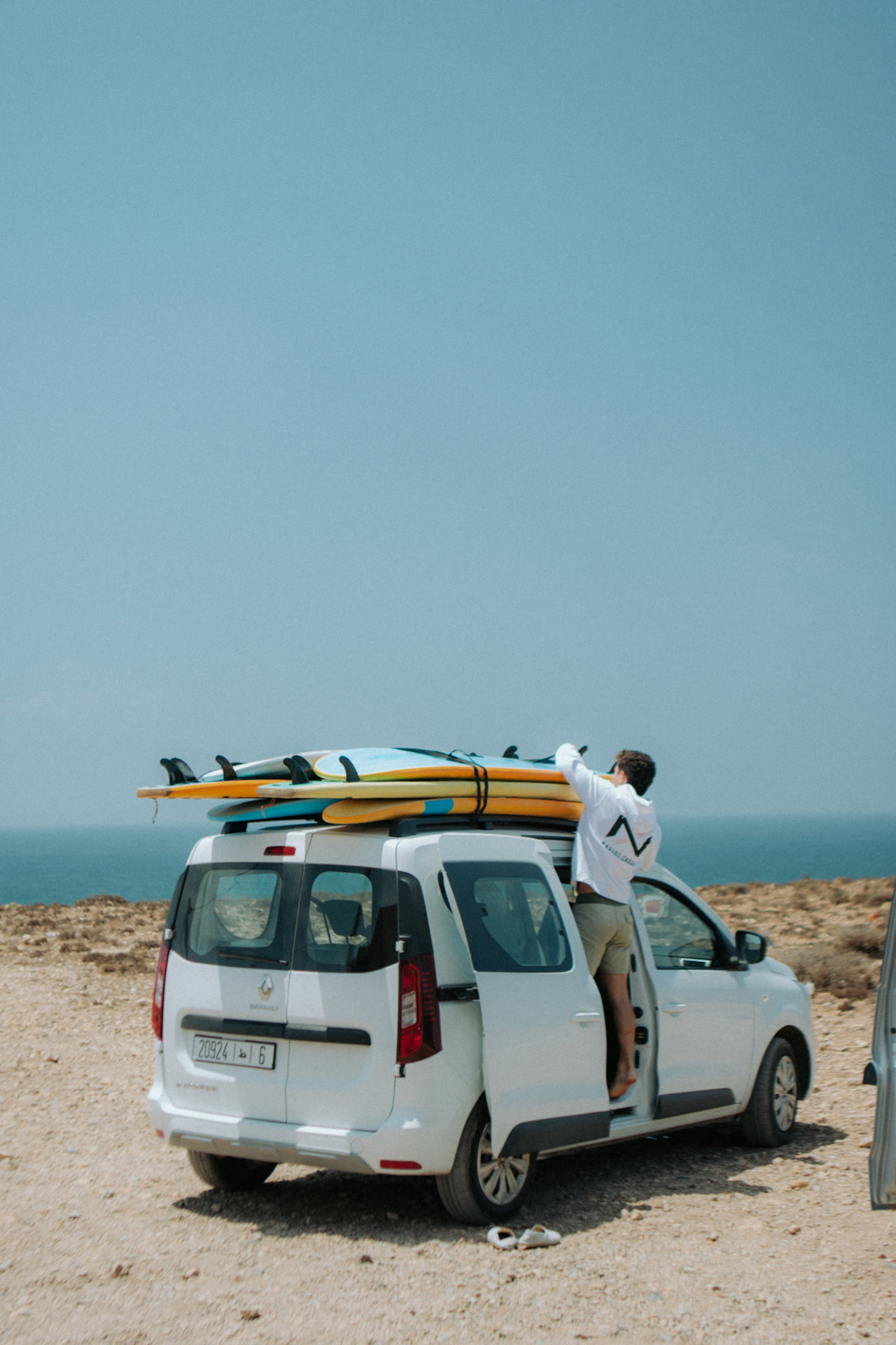 Amigo prende pranchas de surf no tejadilho de uma carrinha junto ao mar